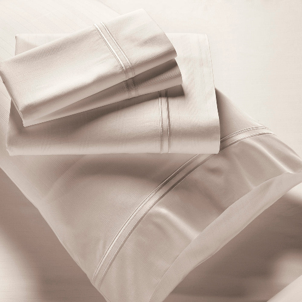 Image showcasing entire Ivory Bamboo Rayon Sheet Set. The image includes: a fitted sheet on the bed, a pillowcase on a pillow, a neatly folded flat sheet, and two neatly folded pillowcases.