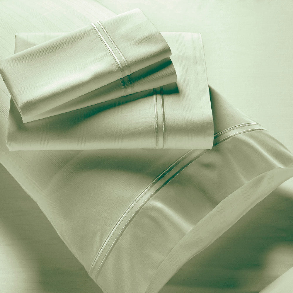 Image showcasing entire Sage Bamboo Rayon Sheet Set. The image includes: a fitted sheet on the bed, a pillowcase on a pillow, a neatly folded flat sheet, and two neatly folded pillowcases.