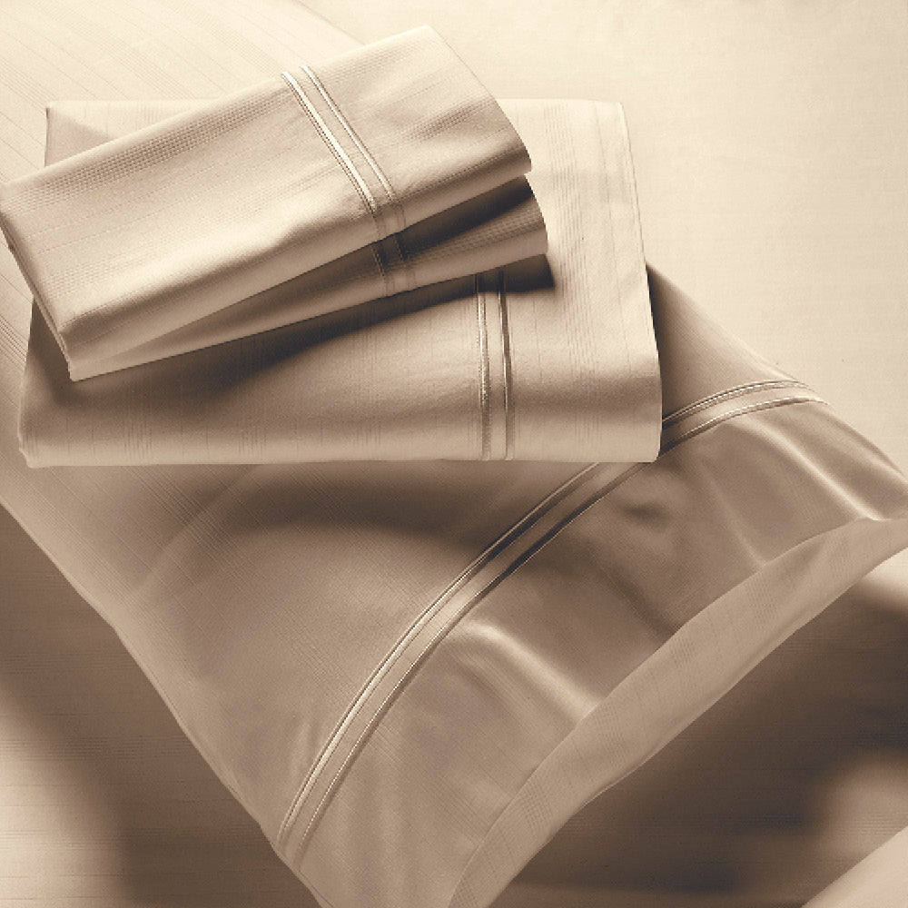Image showcasing entire Sand Bamboo Rayon Sheet Set. The image includes: a fitted sheet on the bed, a pillowcase on a pillow, a neatly folded flat sheet, and two neatly folded pillowcases.