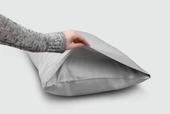 Image of a hand holding open the side of a Dove Gray Recovery Pillowcase showcasing the enveloping design