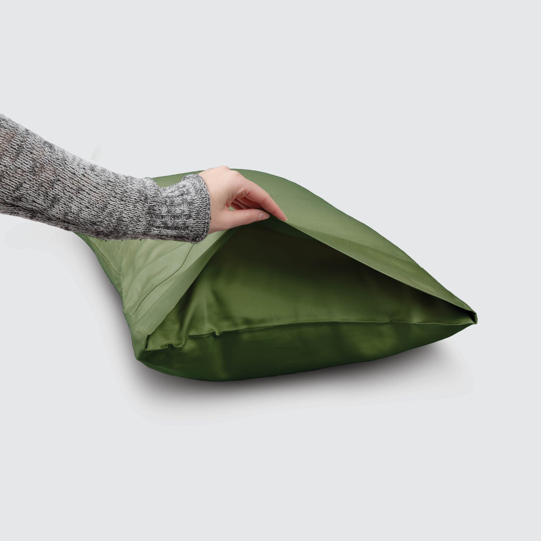Image of a Moss Recovery Viscose Pillowcase on a pillow with a hand lifting up the edge to showcase the enveloping design