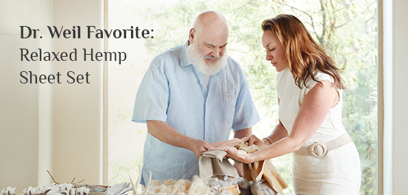 Dr. Andrew Weil and a woman feeling fabric swatches in front of a table with various fabrics and materials. A caption in the top left corner reads: Dr. Weil Favorite: Relaxed Hemp Sheet Set