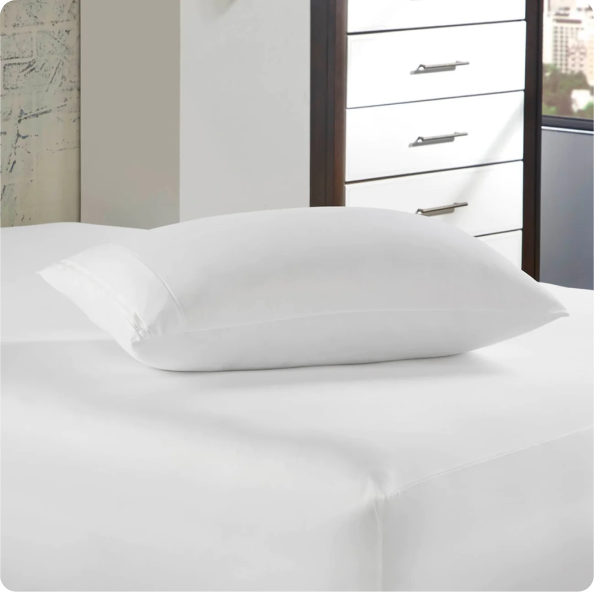 Image of a pillow with a Pillow Protector on a white bed