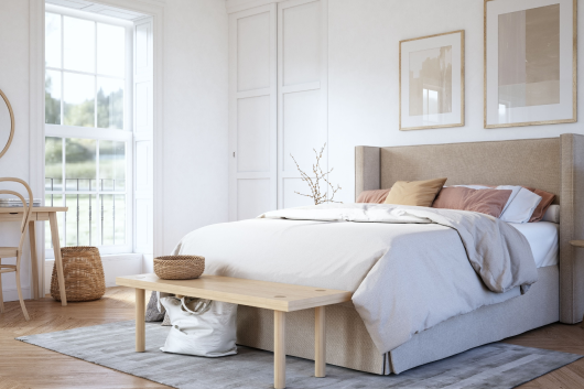 Image of a neatly made bed in a neutral tan and white colored room