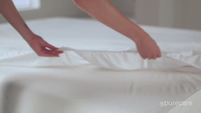 Video of a person putting a Cooling Mattress Protector on a mattress. The video then shows a cup of spilled water on the protector. The person pulls the protector up showing that there was no moisture underneath. The person then takes the protector off and places it in a laundry basket.