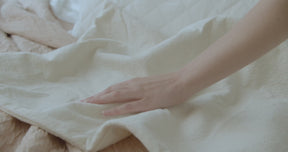 Video of a hand lightly feeling the Signature Mattress Protector laid out over a bed