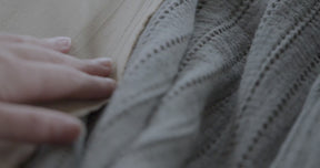 Video of a woman's hand slowly and softly feeling the texture of the Agave Ridgeback Coverlet