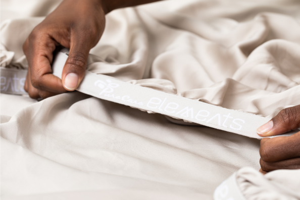 Image of a person folding over the 1" elastic band on the fitted sheet of all Elements sheet sets
