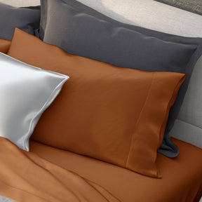 Image of various pillows on a bed with the middle one showcasing the Clay Recovery Viscose Pillowcase