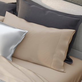 Image of various pillows on a bed with the middle one showcasing the Ivory Recovery Viscose Pillowcase