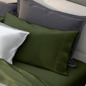 Image of various pillows on a bed with the middle one showcasing the Moss Recovery Viscose Pillowcase