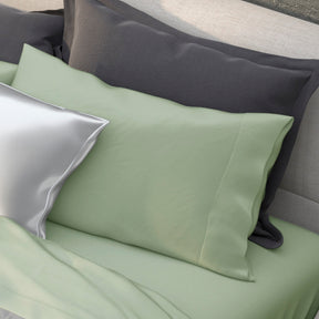 Image of various pillows on a bed with the middle one showcasing the Sage Recovery Viscose Pillowcase