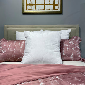 Image of a neatly made bed with a pink floral duvet and three Euro Quilted Pillow Inserts