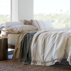 Image of a made bed with a large window behind it. The bed showcases Ochre Garment Washed Percale Sheets, Agave Ridgeback Coverlet, and Sonoran Duvet Cover.