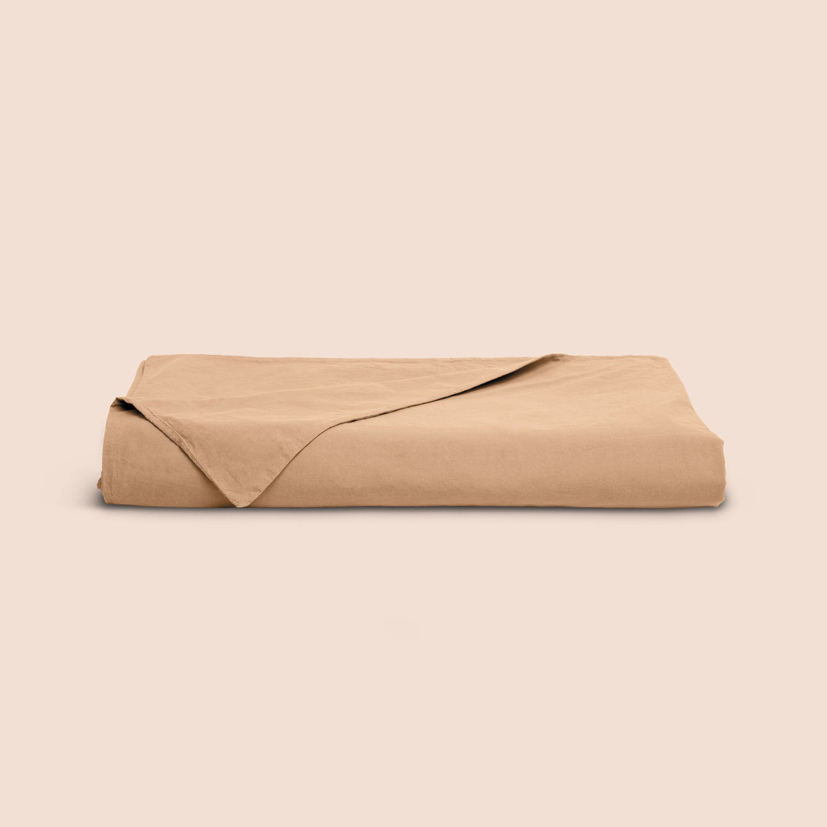 Image of an Ochre Garment Washed Percale Duvet Cover neatly folded with one corner draped towards the front on a light pink background
