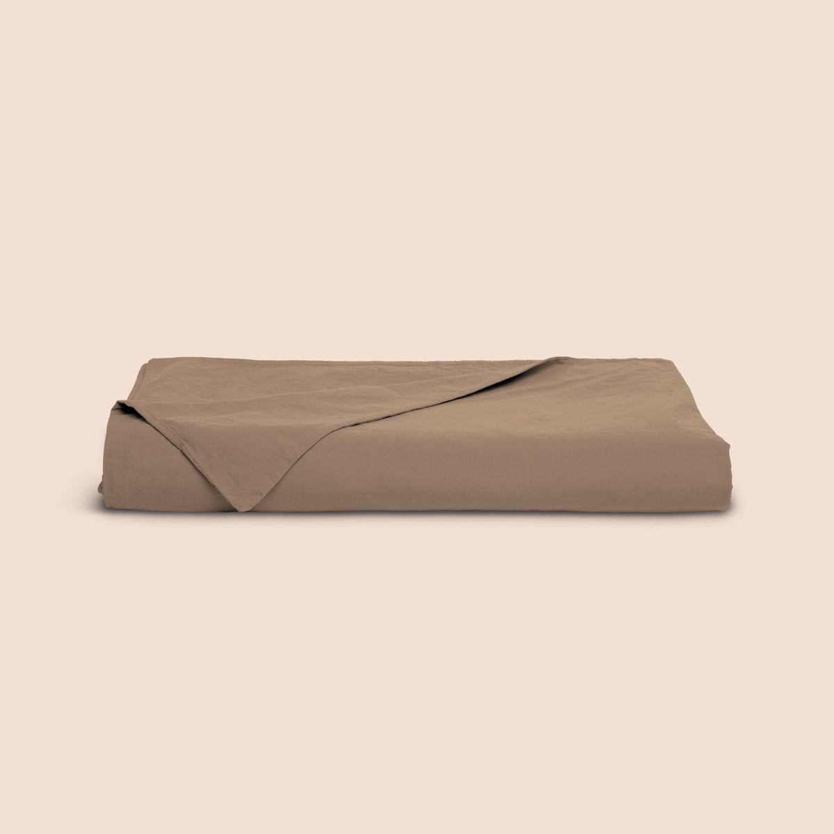 Image of a Desert Sand Garment Washed Percale Duvet Cover neatly folded with one corner draped towards the front on a light pink background