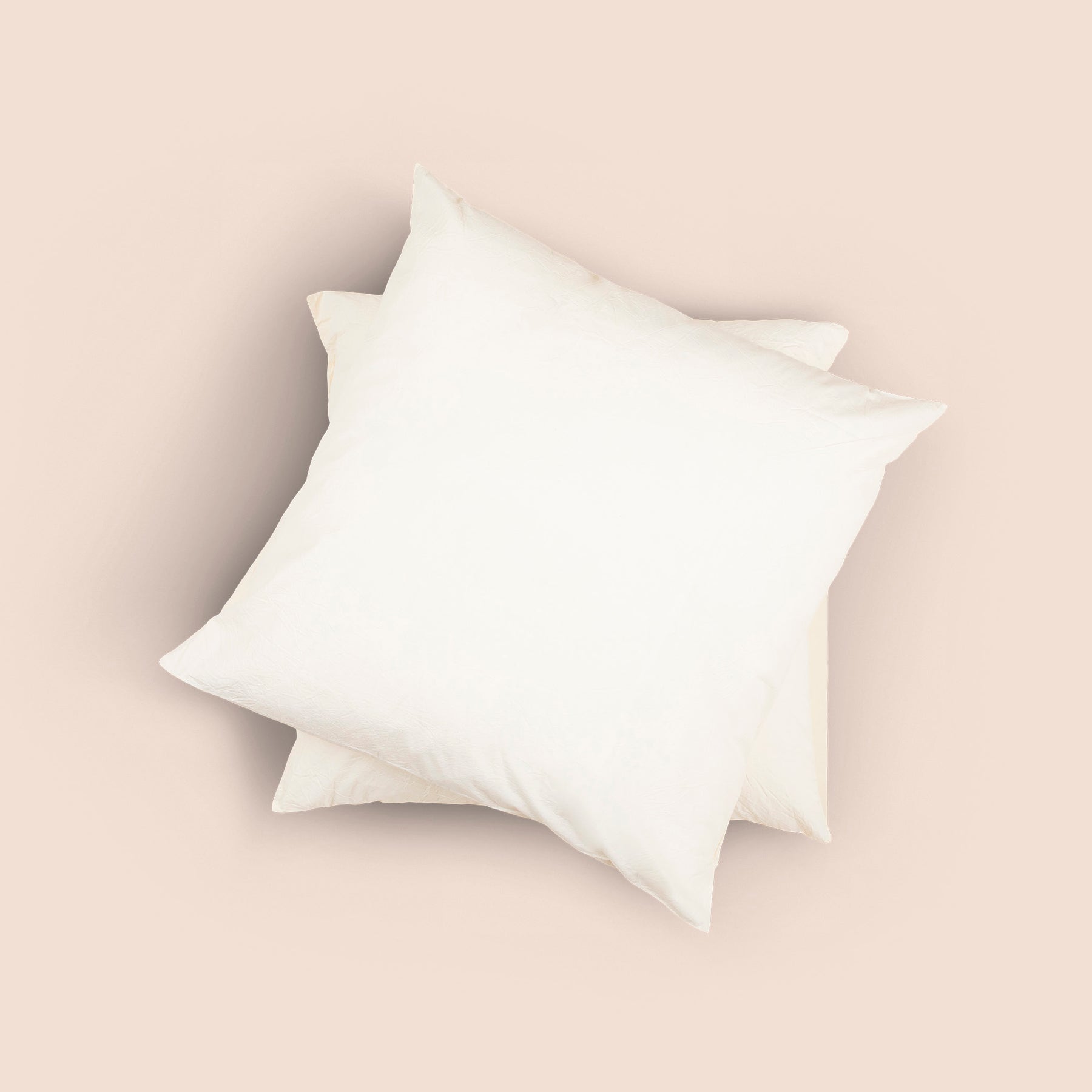 Image of the top of the Ecru Euro-sized Garment Washed Percale Pillow Sham on two Euro pillows stacked on top of one another with a light pink background