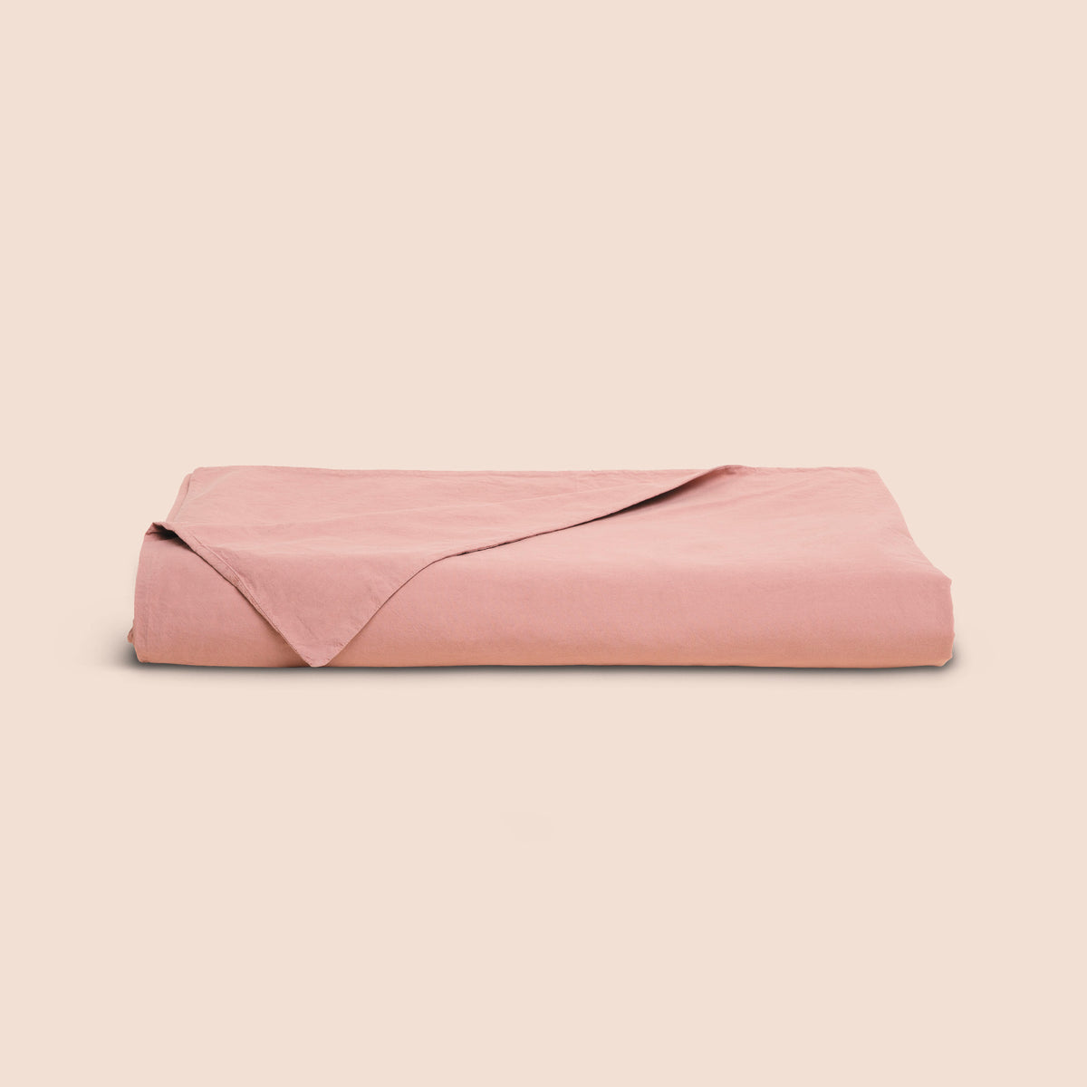 Image of a Pink Sandstone Garment Washed Percale Duvet Cover neatly folded with one corner draped towards the front on a light pink background