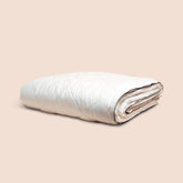 Image of off-white neatly folded duvet insert on light pink background