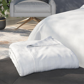 Image of a neatly folded White Duvet Cover + Cooling with one corner folded back on a gray stool at the foot of a bed