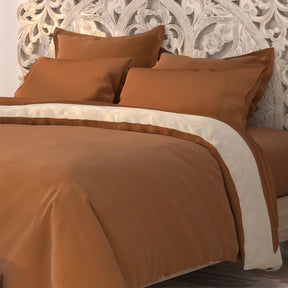 Image of a bed with clay sheets and the Ivory/Clay Duvet Cover + Cooling and Pillow Shams + Cooling with the clay side facing up