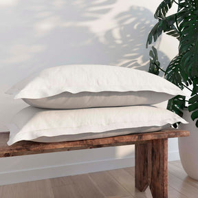 Image of two White Pillow Shams + Cooling on pillows stacked on a wooden bench