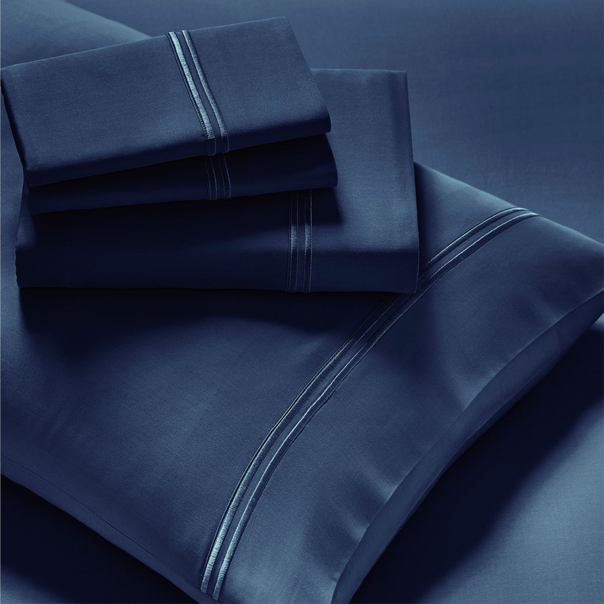 Image showcasing entire Celestial Blue Refreshing TENCEL™ Lyocell Sheet Set. The image includes: a fitted sheet on the bed, a pillowcase on a pillow, a neatly folded flat sheet, and two neatly folded pillowcases.