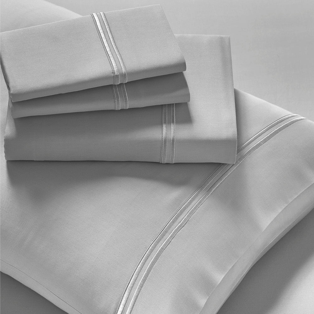 Image showcasing entire Dove Gray Refreshing TENCEL™ Lyocell Sheet Set. The image includes: a fitted sheet on the bed, a pillowcase on a pillow, a neatly folded flat sheet, and two neatly folded pillowcases.