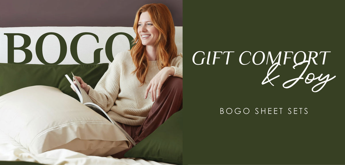 Image of a woman sitting up in bed reading a book with green Moss green and Ivory sheets on the bed with the word "BOGO" in green on the white headboard of the bed. To the right of the image is a dark green background with the words "Gift Comfort & Joy BOGO Sheet Sets" in white letters