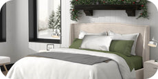 Image of a newly made bed with a White Duvet Cover + Cooling, gray blanket, Silver Pure Silk Pillowcase, and Moss Soft Touch TENCEL™ Modal Sheets with a wintery background. 