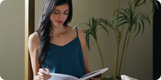 Image of a woman sitting on the edge of a bed reading