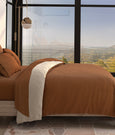 Side view of a bed with Clay Soft Touch Sheets and Clay/Ivory Duvet Cover and Pillow Shams with the clay side facing up