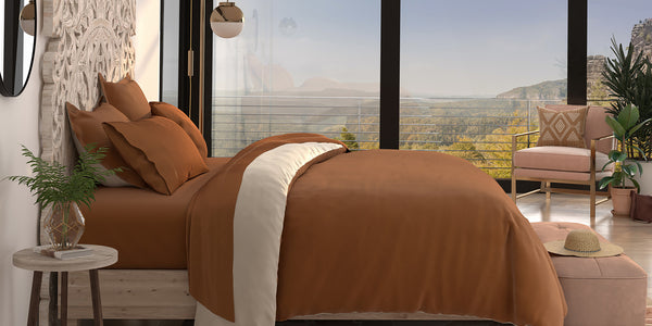 Side view of a bed with Clay Soft Touch Sheets and Clay/Ivory Duvet Cover and Pillow Shams with the clay side facing up
