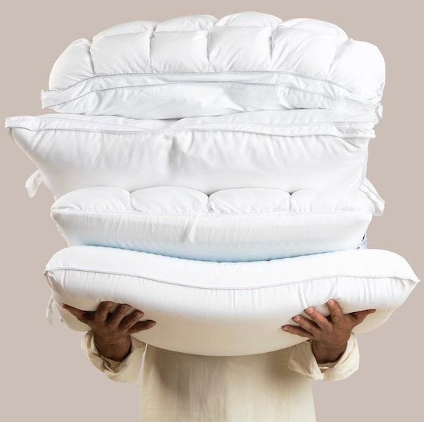 Image of a man holding a stack of pillows in front of his face