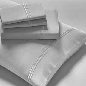 Image showcasing entire Dove Gray Refreshing TENCEL™ Lyocell Sheet Set. The image includes: a fitted sheet on the bed, a pillowcase on a pillow, a neatly folded flat sheet, and two neatly folded pillowcases.