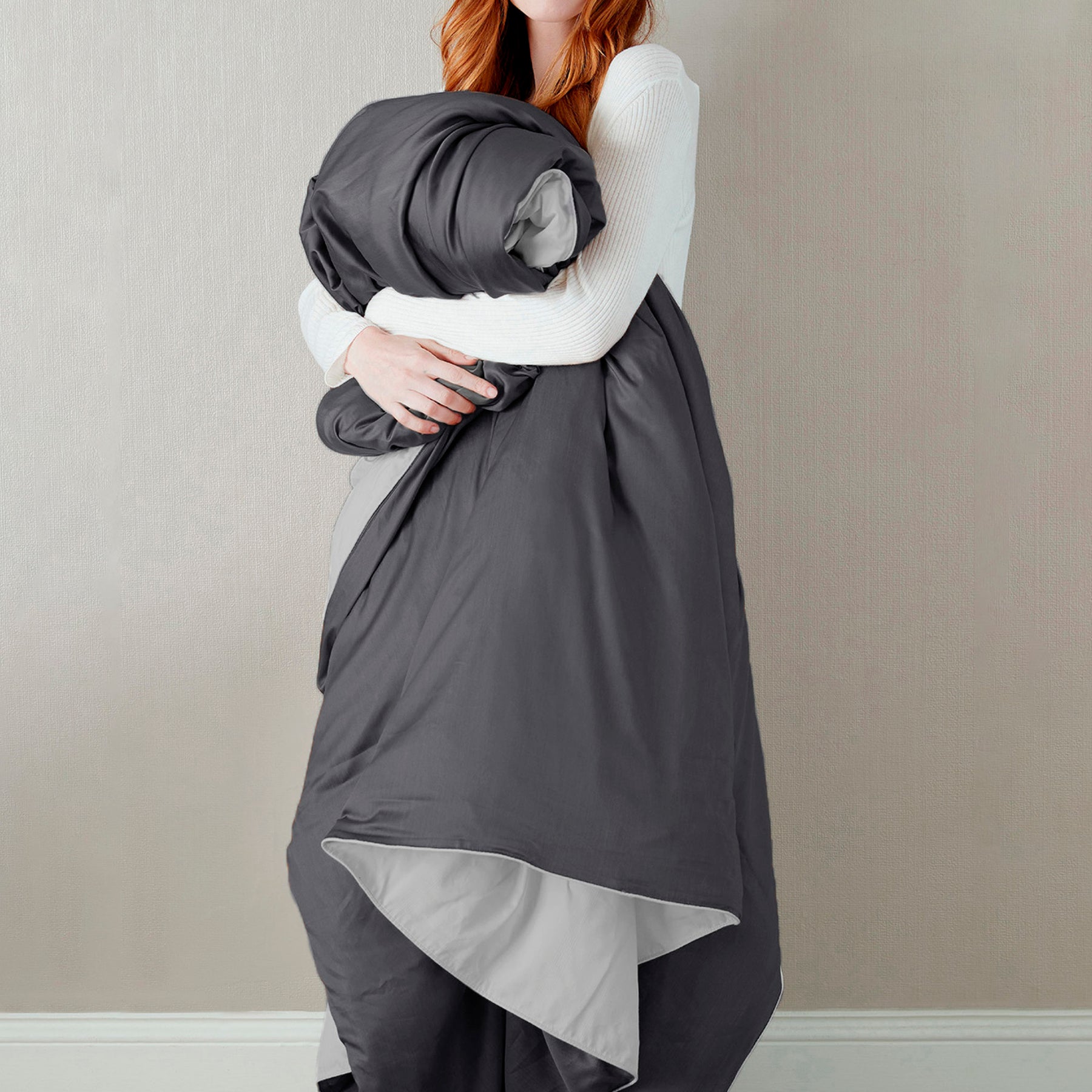Image of a woman standing and holding the Shadow/Dove Gray Soft Touch Duvet Cover against her