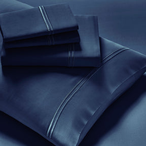 Image showcasing entire Celestial Blue Refreshing TENCEL™ Lyocell Sheet Set. The image includes: a fitted sheet on the bed, a pillowcase on a pillow, a neatly folded flat sheet, and two neatly folded pillowcases.