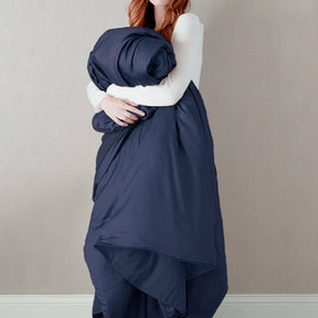 Image of a woman standing and holding the Midnight Soft Touch Duvet Cover against her
