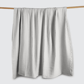 Image of a Bright White Everyday Cotton Coverlet hanging and draped over a wooden rod on a white background