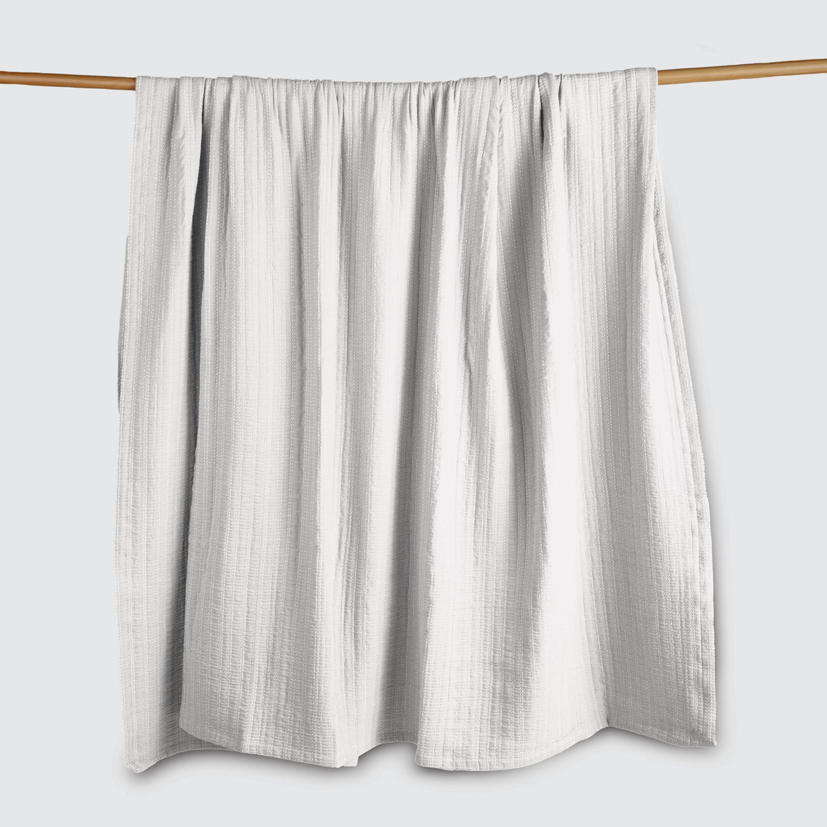 Image of a Bright White Everyday Cotton Coverlet hanging and draped over a wooden rod on a white background