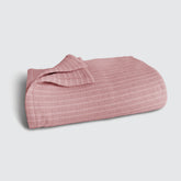 Image of an Ash Rose Everyday Cotton Coverlet folded up on a white background