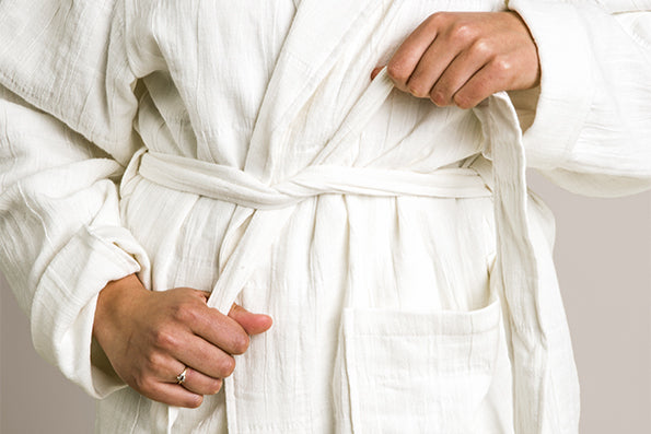 Image of person wearing a white Featherweight Robe with a close-up of tying the belt across their waist