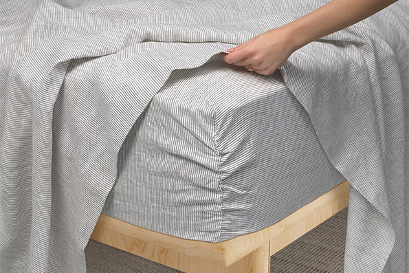 Image of Pinstripe Relaxed Hemp fitted sheet showcasing the Precision-Fit® Corner on the edge of a mattress
