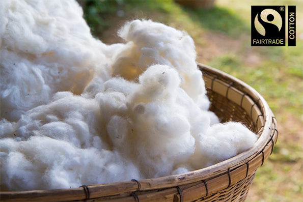 Image of a basket filled with cotton in an outdoor setting with the Fairtrade® Cotton logo in the top right corner
