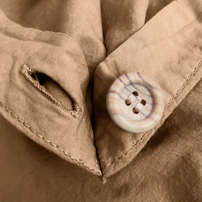 Close-up image of the button and button hole on the corner of an Ochre Garment Washed Percale Duvet Cover. 