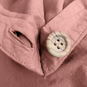 Close-up image of the button and button hole on the corner of a Pink Sandstone Garment Washed Percale Duvet Cover. 