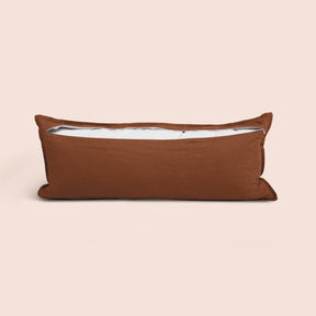 Image of the back of the Cacao Blended Linen Lumbar Pillow Cover on a lumbar pillow with the back zipper open on a light pink background
