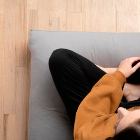 Image of woman sitting cross-legged on a meditation cushion with Stone Gray Blended Linen Meditation Cushion Cover