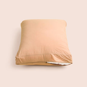 Image of Ochre Garment Washed Percale Meditation Cushion Cover showcasing a slightly opened zipper with a meditation cushion inside on a light pink background 