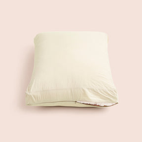 Image of Ecru Garment Washed Percale Meditation Cushion Cover showcasing a slightly opened zipper with a meditation cushion inside on a light pink background 